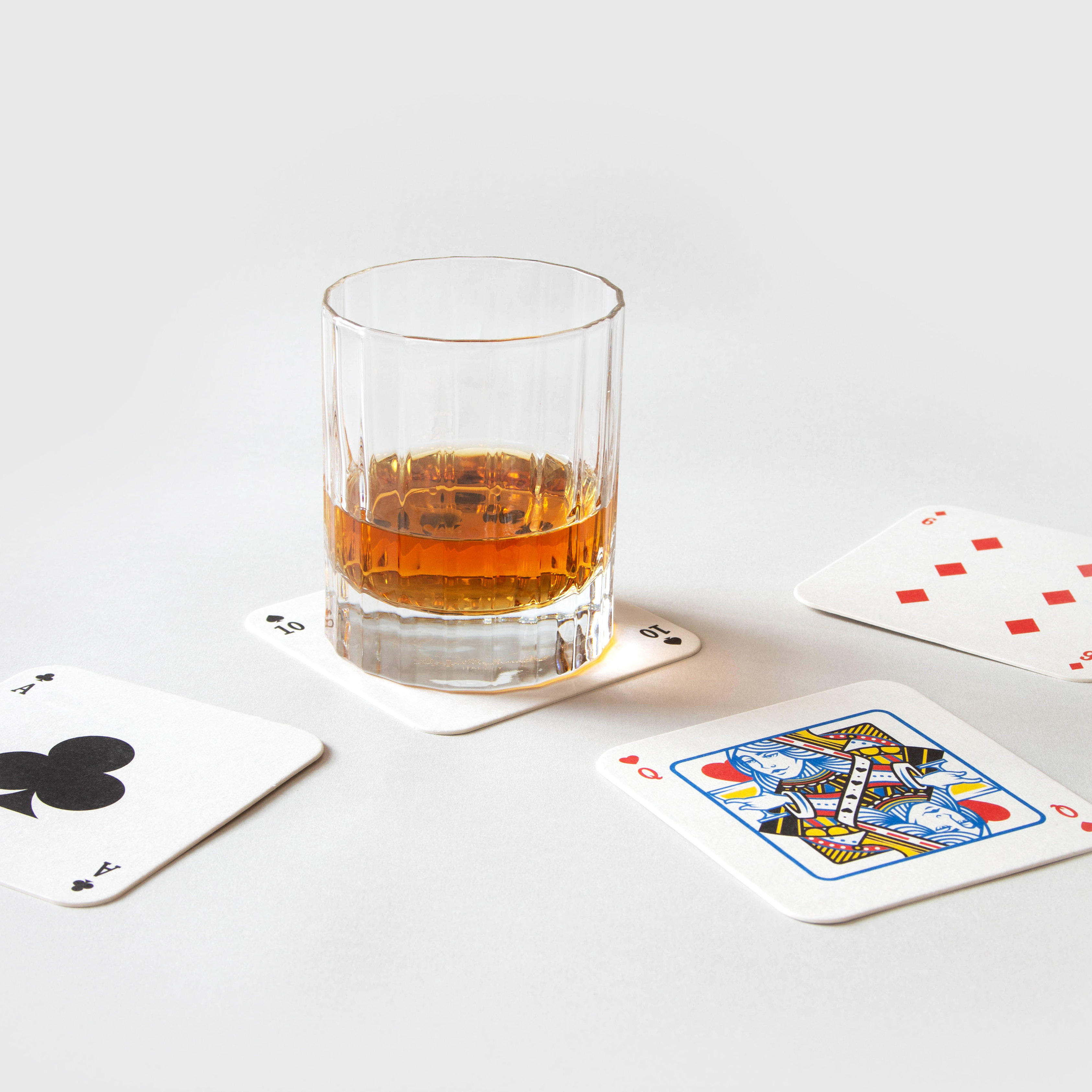 Glass of whiskey on playing mat coasters