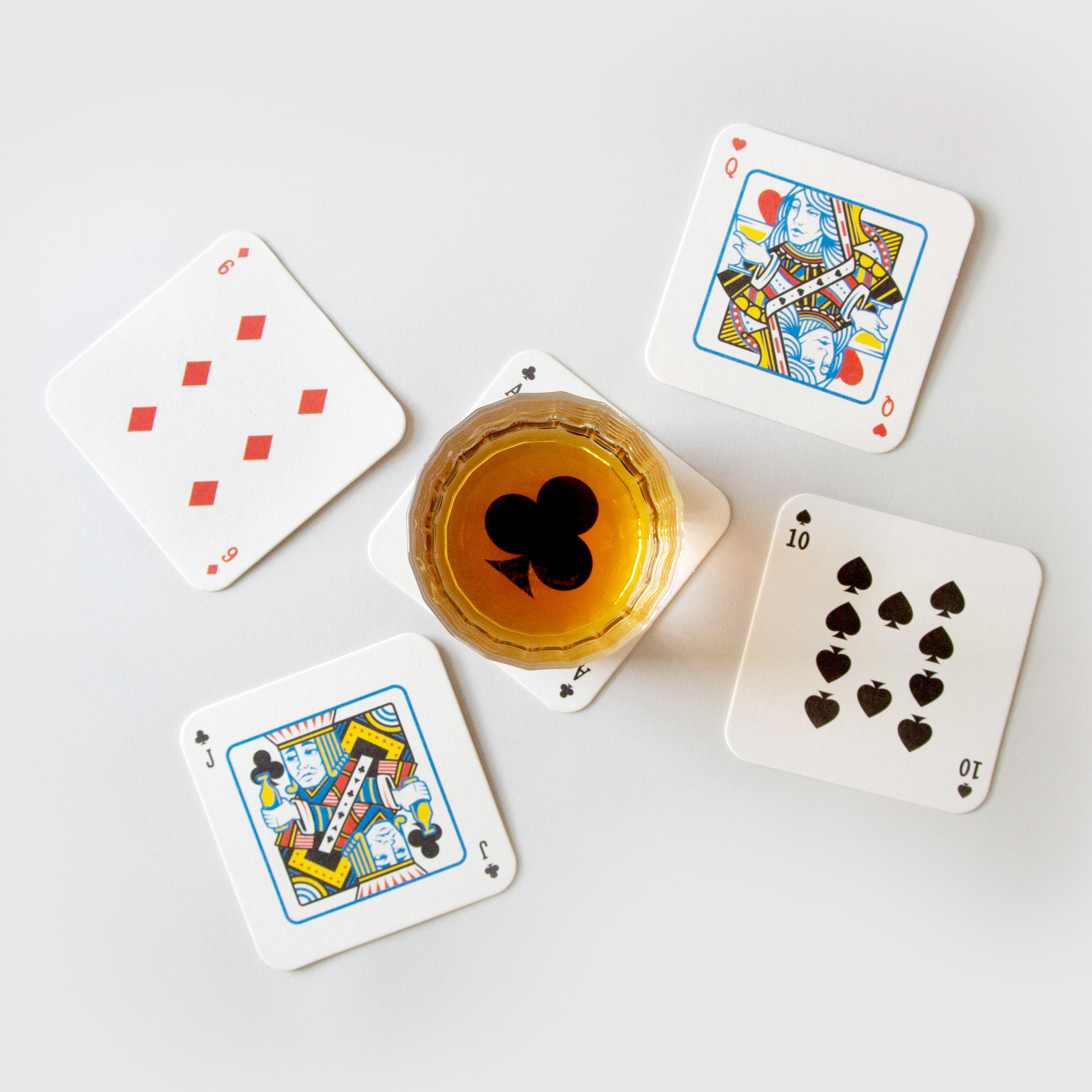 Glass of whiskey on drink mat playing cards