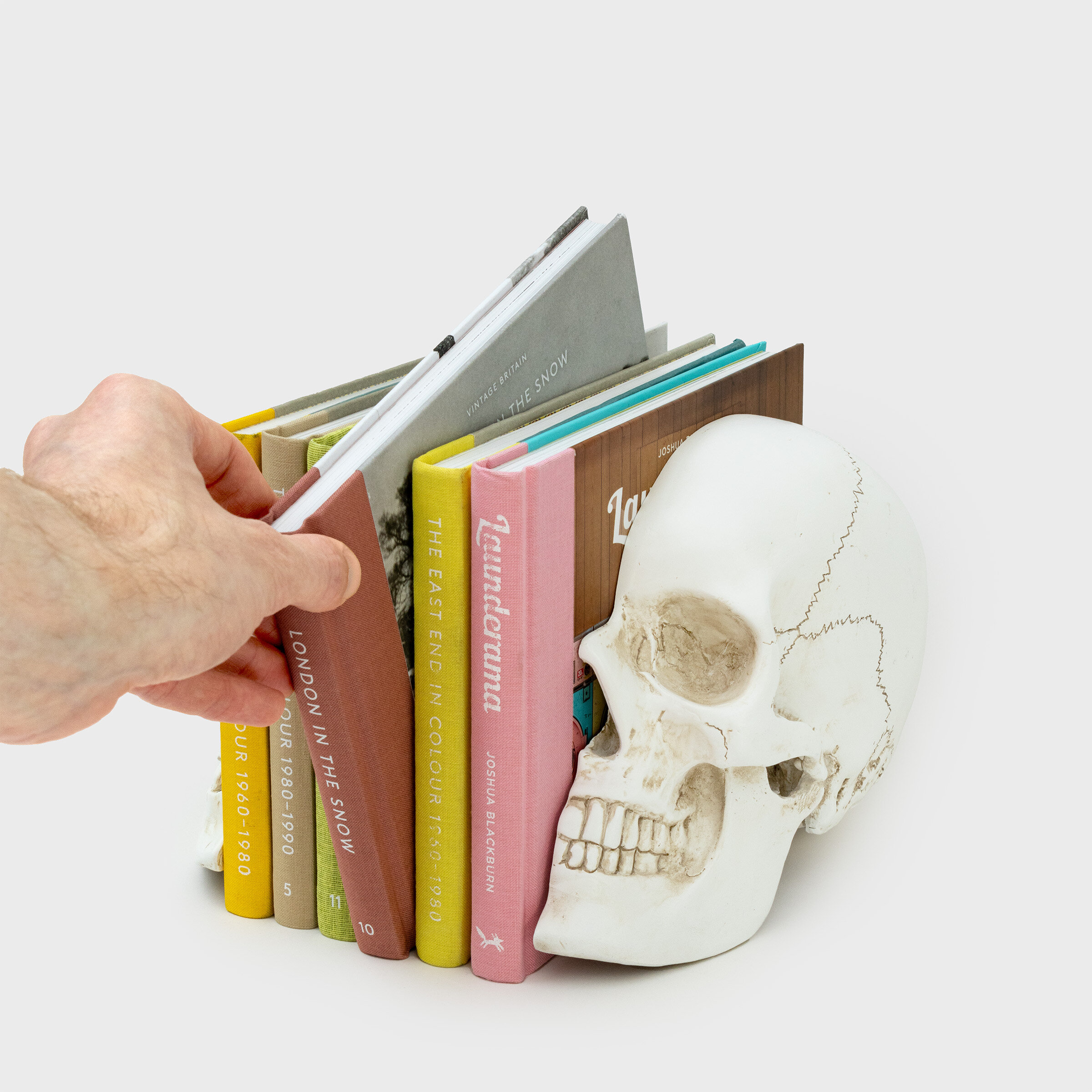 hand picking book from between skull bookends