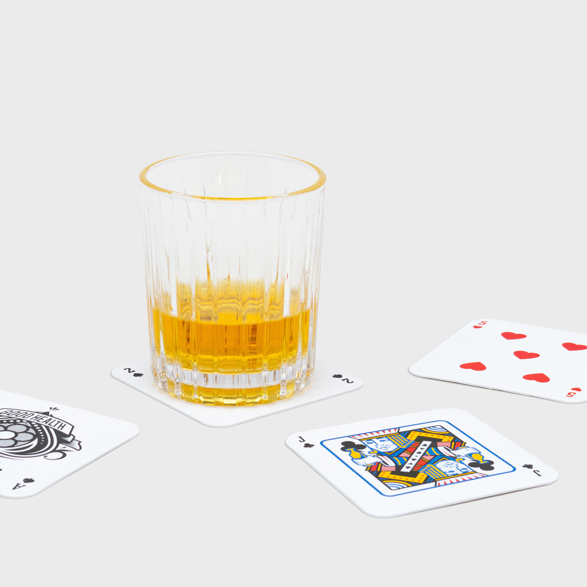 Glass of whiskey on playing mat coasters